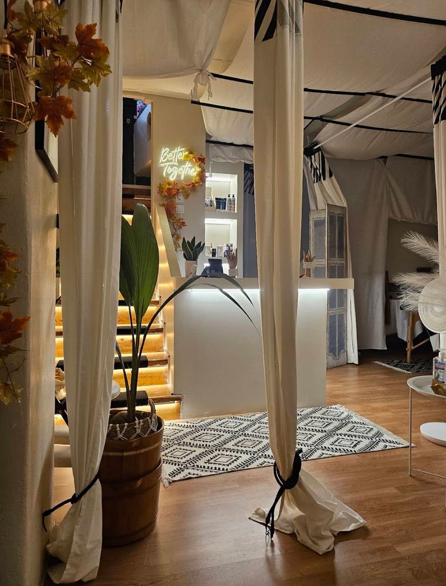 Draped linen curtains, plants and patterned rug in the reception lounge of Enyo Thai spa in Athens